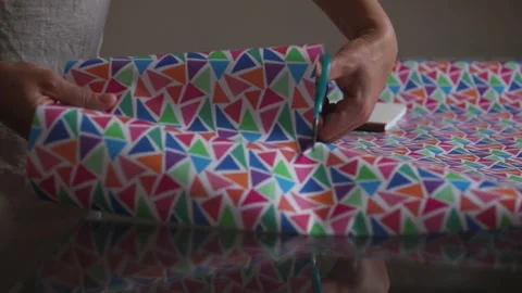 Hands Prepare Colorful Geometric Patterned Wrapping Paper for Creative Packaging Stock Footage 316837523
