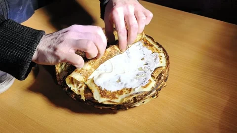 Hands prepare a layered dish with cream on a wooden table in an indoor kitchen s Vídeo Stock 328444654