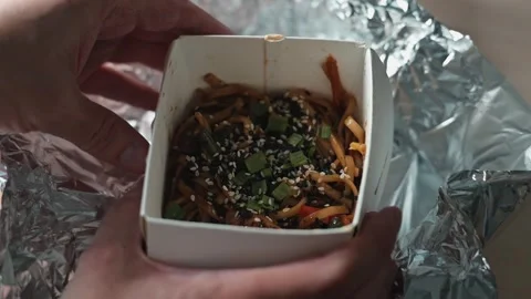Hands prepare to open a takeout container filled with colorful food. Stock Footage 338186556