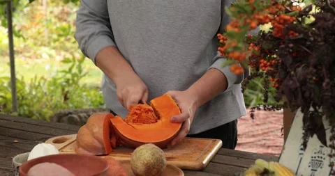 Hands prepare raw pumpkin for cooking and clean off seeds from inside with knife Stock Footage 165289141