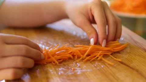 Hands preparing with carrot spring rolls Slicing of peeled carrots on a wooden Video stock 305985648
