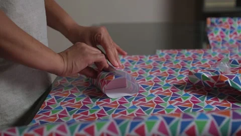 Hands Preparing Colorful Patterned Wrapping Paper for Packaging Gifts Stock Footage 316836890