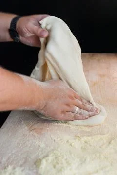 Hands preparing dough basis for pizza on the wooden table, close-up Stock Photos