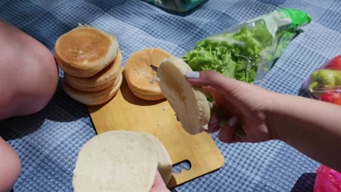 Hands Preparing Fresh Hamburger Buns on Wooden Board During Picnic Stock Footage 341997614