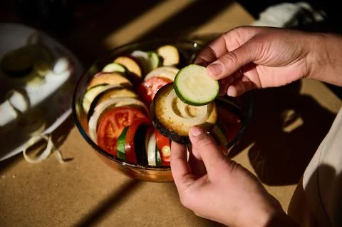 Hands Preparing Fresh Sliced Vegetables in Sunlit Kitchen Stock Photos