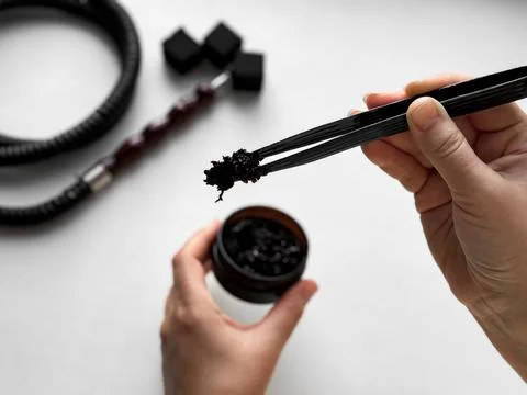 Hands preparing hookah, close up of charcoal and tobacco setup Stock Photos