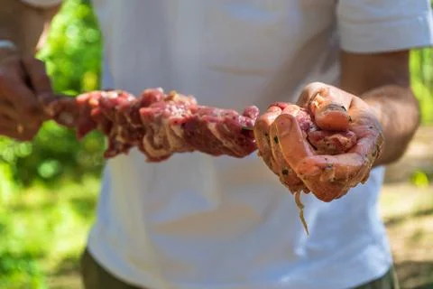 Hands preparing marinated meat skewer before barbecue cooking Foto stock