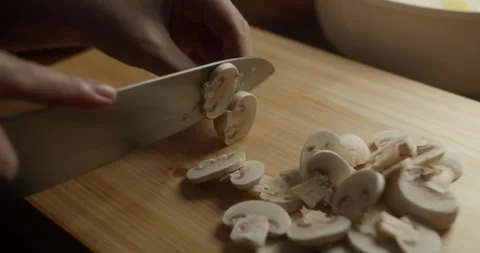 Hands preparing mushrooms with a kitchen knife for homemade cooking in warm Vídeo Stock 327686912