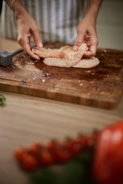 Hands preparing raw chicken breast on wooden board Stock Photos