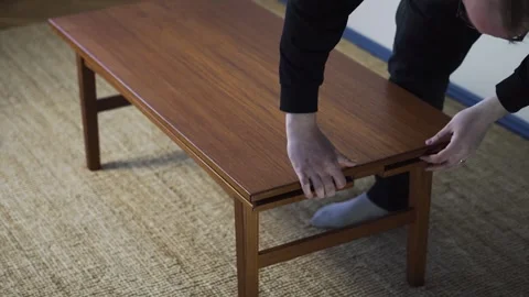 Hands Preparing Teak Coffee Table for Sale in a Home Furniture Setting Stock Footage 333725360