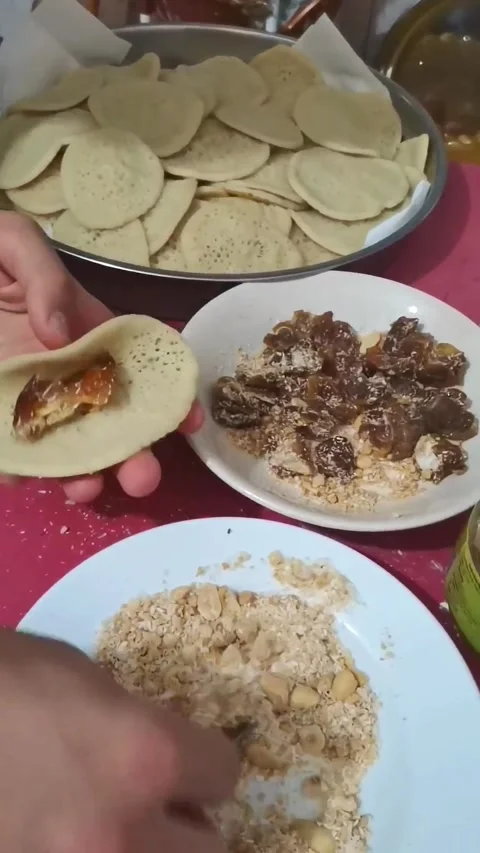 Hands preparing traditional Atayef Arabic pancakes, stuffing them with nuts and 動画素材 333525307