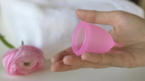 Hands presenting reusable menstrual cup in palm. Visual showing modern personal Stock Footage 330460001