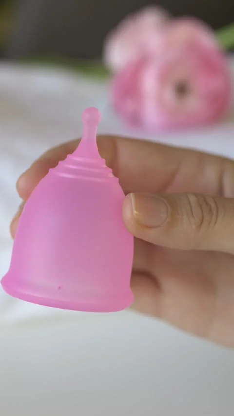 Hands presenting reusable menstrual cup in palm. Visual showing modern personal Stock Footage 330480677