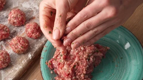 Hands press and shape a seasoned ground meat mixture. Stock Footage 255665202
