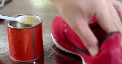 Hands press down on a sneaker to ensure proper bonding after applying glue. Stock Footage 313495570