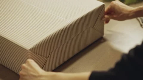 Hands Press the Striped Wrapping Paper Firmly Around a Christmas Gift - Close Up Stock Footage 332684199