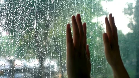 Hands pressed against a glass window covered in raindrops Stock-Footage 332285068