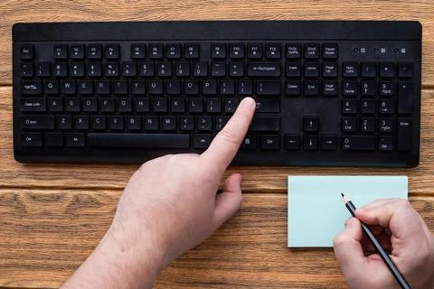 Hands Pressing Computer Keyboard Keys While Writing With Pencil In Notepad... Stock Photos