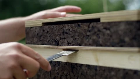 Hands Pressing Cork Insulation Into Timber Wall Panel, Outdoor Bench, Macro Stock Footage 341296191