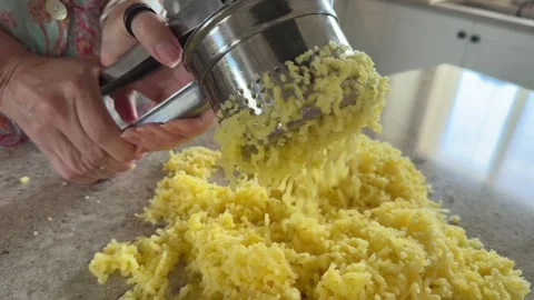 Hands Pressing Potatoes Through a Ricer in Home Kitchen Stock Footage 343009197