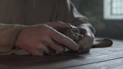 Hands of a prisoner slowly breaking a piece of bread inside a gloomy dungeon Vídeo Stock 340824181