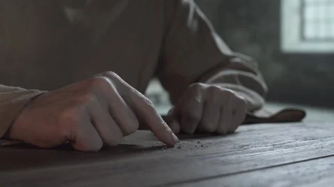 Hands of prisoner slowly gathering dry breadcrumbs on a rustic wooden table Stock Footage 337930244