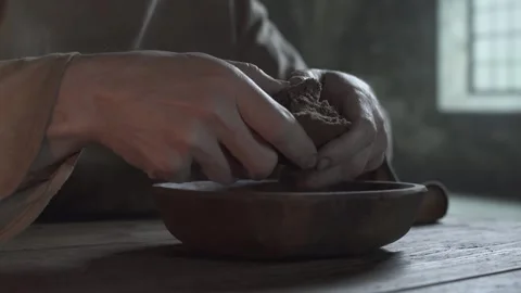 Hands of a prisoner tearing a rye bread chunk over a bowl inside a gloomy cell Stock Footage 340079614