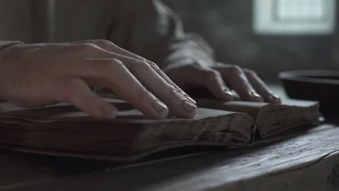 Hands of a prisoner tracing lines in a book inside a dungeon Vídeo Stock 340080058