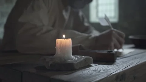Hands of prisoner writing and warming over a candle inside a gloomy cell Video stock 341009543