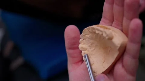 Hands probing upper dental plaster model with metal instrument during closeup Stock Footage 347869950