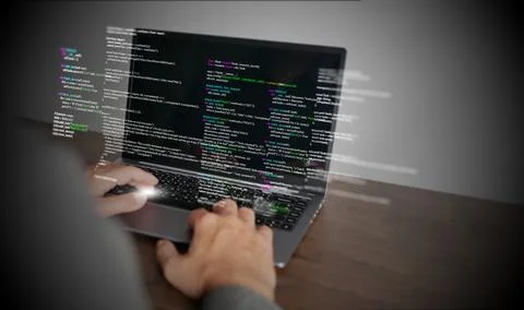 Hands of a programmer types on a laptop displaying programming code, symbol.. Photos