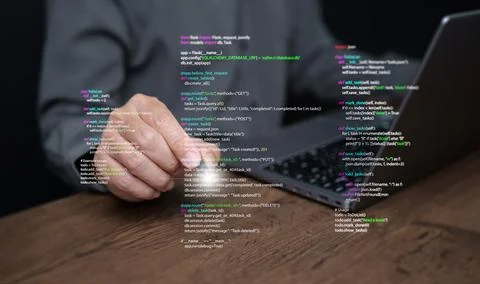 Hands of a programmer types on a laptop displaying programming code, symbol.. Stock Photos