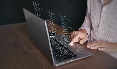 Hands of a programmer types on a laptop displaying programming code, symbol.. 写真素材