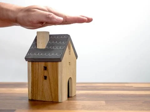 Hands protect a small model of a house isolated on white background Foto stock