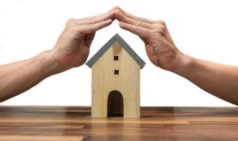Hands protecting house model on table, real estate Stock Photos