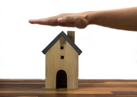 Hands protecting house model on table, real estate Stock Photos