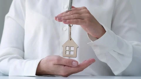 Hands protecting keychain shaped house. Home and real estate property insurance Stock Footage 258409184