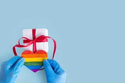 Hands in protective blue gloves hold a homemade rainbow paper heart and a gif Stock Photos