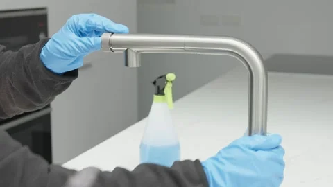 Hands in protective glove cleaning a modern tap with rag Видео 158577437