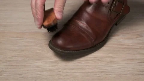 Hands in protective gloves clean brown leather shoes with a brush Stock Footage 147380230