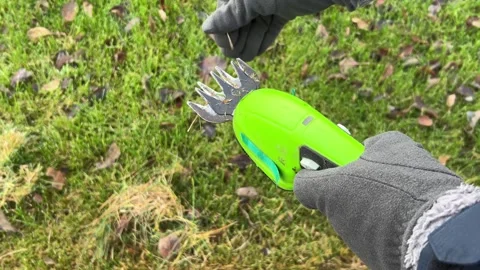 Hands in protective gloves cleaning blade of garden trimmer from dry grass Vidéo 321063167