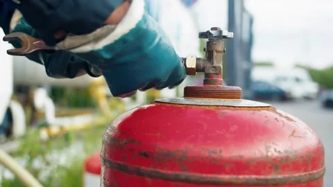 Hands in protective gloves screwing an adapter onto the valve of a gas cylinder 库存影片 312964177