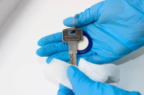 Hands in protective gloves wipe the keys to the front door with a napkin. Foto stock