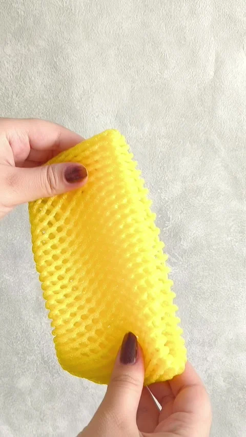 Hands pull foam mesh for fruit packaging. Packaging for transportation, delivery Stock Footage 332409821