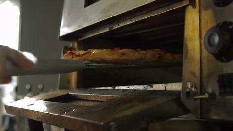 Hands pull out of the oven hot pizza with cheese and puts it on the table. Stock Footage 113214336