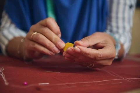 Hands pull sewing thread through beeswax over marked fabric while preparing.. Stock Photos