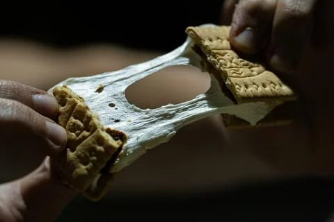 Hands pulling apart marshmallow smore campfire dessert Stock Photos