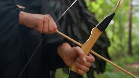 Hands Pulling Bowstring with Arrow Ready to Shoot in Forest Stock Footage 321595618