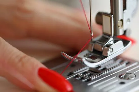 Hands pulling red thread in sewing machine needle Stock Photos