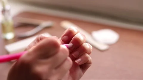 Hands pushing back cuticles with a pink tool during a home manicure, close-.. Stock Footage 333845313
